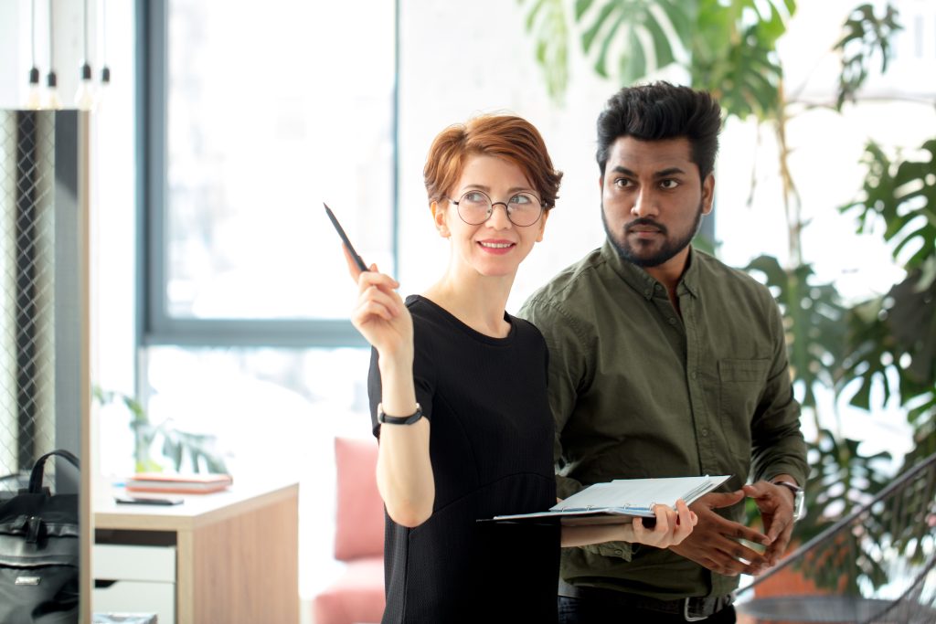 business partners standing in office building and talking about deals, woman showing office