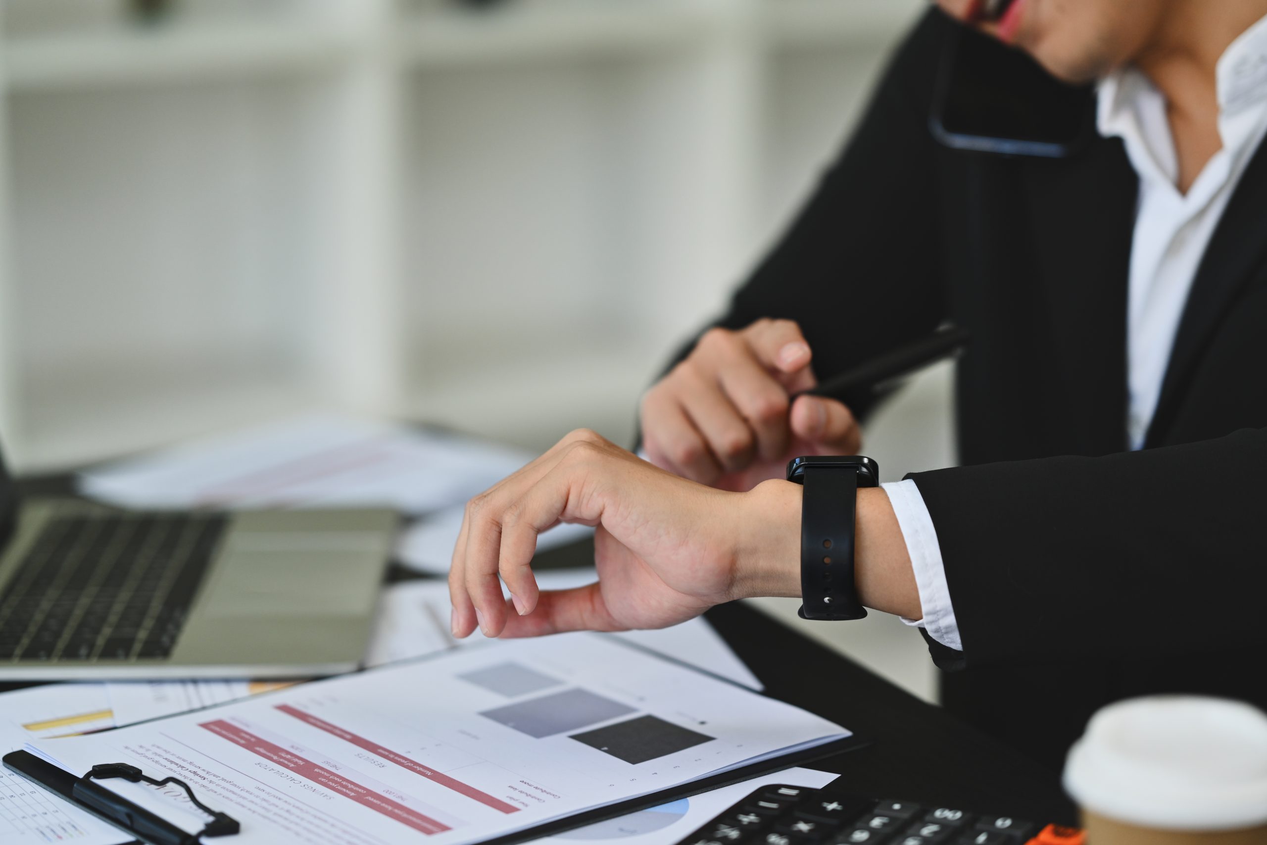 cropped shot of young businessman in formal suit checking time on wrist watch for appointment