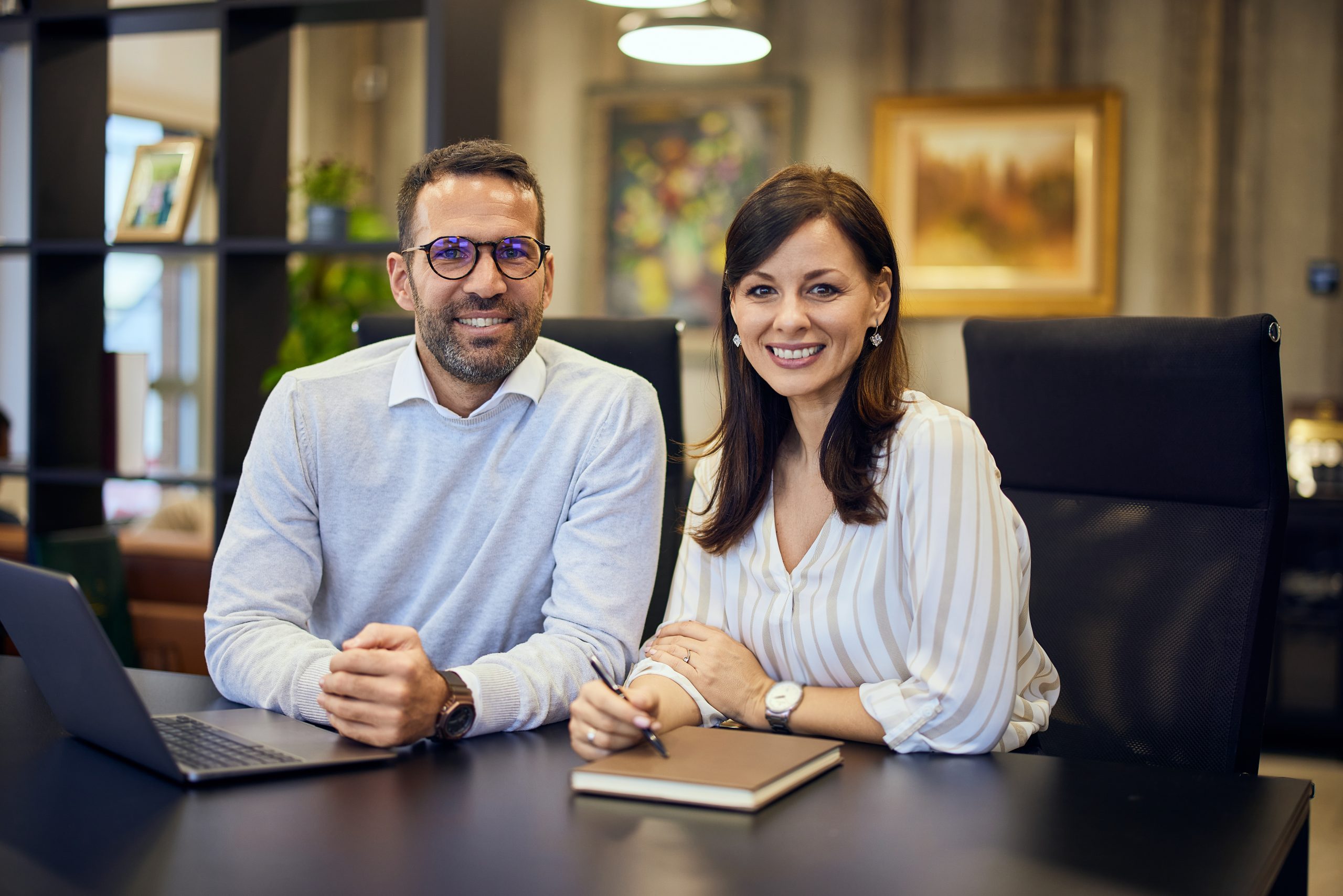portrait of a smiling businesswoman and businessman working on the same project at the office.